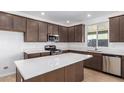 Modern kitchen with dark wood cabinets, stainless steel appliances, and an island at 13248 W Hackamore Dr, Peoria, AZ 85383