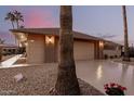 Tan house with a two-car garage and mature palm trees in front at 21610 N Sunglow Dr, Sun City West, AZ 85375