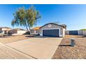 Single-story home with gray exterior, dark garage door, and a tree in front at 13525 S Burma Rd, Arizona City, AZ 85123