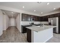 Modern kitchen with dark cabinetry, granite island, and stainless steel appliances at 35625 W Mallorca Ave, Maricopa, AZ 85138