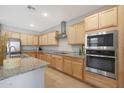 Modern kitchen with light wood cabinets, granite counters, and stainless steel appliances at 15072 W Mckinley St, Goodyear, AZ 85338