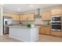 Modern kitchen with light wood cabinets, granite counters, and stainless steel appliances at 15072 W Mckinley St, Goodyear, AZ 85338