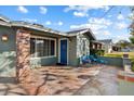 Stone patio with seating area, blue door entry, and brick pillars at 5056 E Weldon Ave, Phoenix, AZ 85018