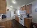 Kitchen with wood cabinets, white appliances, and dark flooring at 8700 E University Dr # 545, Mesa, AZ 85207