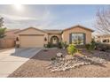 Tan house with a two-car garage and nicely landscaped front yard at 2025 W Desert Spring Way, San Tan Valley, AZ 85144