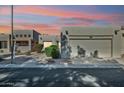 Attractive tan stucco home with a two-car garage at dusk at 14444 W Moccasin Trl, Surprise, AZ 85374