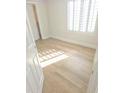 Sunlit bedroom with wood-look flooring, white walls, and plantation shutters at 18802 N 44Th Pl, Phoenix, AZ 85050