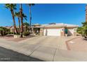 Single-story home with a two-car garage and palm trees at 15140 W Gunsight Dr, Sun City West, AZ 85375