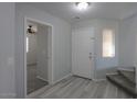 Home entryway with gray wood-look flooring, a staircase and white door at 40092 W Hayden Dr, Maricopa, AZ 85138