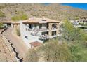 Luxury home with stone accents, balconies, and a paved driveway nestled in the mountains at 11328 E Dreyfus Ave, Scottsdale, AZ 85259