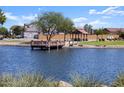 Community lake with a wooden deck, ramadas, and lush green grass at 36971 W Prado St, Maricopa, AZ 85138