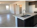 Kitchen island with white countertop, dark cabinets, and stainless steel faucet at 31730 N Waddle Ln, San Tan Valley, AZ 85143