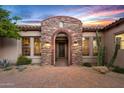 Close-up of the arched stone entryway with front door and desert landscaping at 36701 N Porta Nuova Rd, Scottsdale, AZ 85262