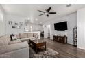 Spacious living room with L-shaped sofa, wood floors, and a large TV at 36909 N Coronado Ln, San Tan Valley, AZ 85140