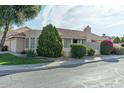 Exterior view of a single-story home with a tiled roof, surrounded by green bushes and a paved driveway at 8033 W Paradise Dr, Peoria, AZ 85345