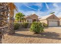 Tan house with a two car garage and palm trees at 15451 W Gunsight Dr, Sun City West, AZ 85375