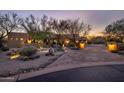 Beautiful desert landscaping and a paved driveway lead to this home at dusk at 33296 N Vanishing Trl, Scottsdale, AZ 85266