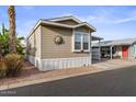 Tan single-wide manufactured home with carport, landscaping, and golf cart at 8865 E Baseline Rd # 1129, Mesa, AZ 85209
