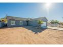 Single-story home with gray exterior, white garage, and desert landscaping under a sunny sky at 993 S Lawson Dr, Apache Junction, AZ 85120