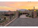 Gated driveway at sunset leading to a luxurious desert home at 8702 E Silver Saddle Dr, Carefree, AZ 85377