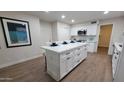 Modern kitchen with white cabinetry, a large island, and wood-look flooring at 4636 E Florian Ave, Mesa, AZ 85206