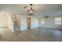 Open-concept living room with wood-look flooring, ceiling fan, and staircase at 6638 W Hughes Dr, Phoenix, AZ 85043