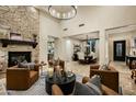 Open-concept living room with a stone fireplace, leather seating, and views of the dining area at 9424 E Hidden Spur Trl, Scottsdale, AZ 85255
