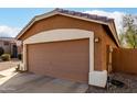 Attached garage with brown door, exterior lighting, and landscaping at 13727 W Marissa Dr, Litchfield Park, AZ 85340