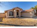 Tan house with a two-car garage and desert landscaping at 12479 W Palm Ln, Avondale, AZ 85392