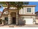 Two-story house with tan exterior, large windows, and a two-car garage at 44344 W Knauss Dr, Maricopa, AZ 85138