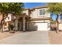 Two-story house with tan exterior, large windows, and a two-car garage at 44344 W Knauss Dr, Maricopa, AZ 85138