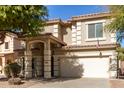 Two-story house with tan exterior, large windows, and a two-car garage at 44344 W Knauss Dr, Maricopa, AZ 85138