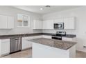 Modern kitchen with white cabinets, granite countertops, and island at 8391 W Mantle Way, Florence, AZ 85132