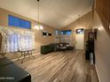 Bright living room with vaulted ceiling, wood-look floors, and gray sectional sofa at 4112 S 249Th Dr, Buckeye, AZ 85326