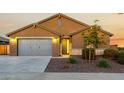 Tan house with gray garage doors and stone accents at 18056 W Wolf St, Goodyear, AZ 85395