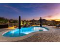 Inviting kidney-shaped pool with water feature at sunset at 26183 W Rosemonte Dr, Buckeye, AZ 85396