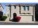 Tan two-story house with a red door and attached two-car garage at 9527 N 82Nd Ln, Peoria, AZ 85345