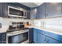 Modern kitchen with stainless steel appliances and dark blue cabinetry at 14850 W Laurel Ln, Surprise, AZ 85379