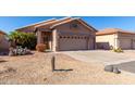 Tan house with two-car garage and desert landscaping at 11553 W Sonoran Ct, Surprise, AZ 85378