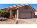 Tan house with two-car garage and desert landscaping at 11553 W Sonoran Ct, Surprise, AZ 85378