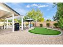 Backyard oasis with putting green, pergola, and patio area at 6113 E Gelding Dr, Scottsdale, AZ 85254