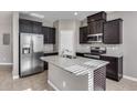 Modern kitchen with dark cabinets, granite island, and stainless steel appliances at 1255 N Arizona Ave # 1276, Chandler, AZ 85225