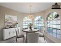 Virtually staged dining area with large windows and chandelier at 11806 N 40Th Pl, Phoenix, AZ 85028