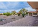 Large backyard with brick patio, fruit trees, and gravel landscaping at 9526 W Cedar Hill Cir, Sun City, AZ 85351