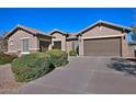 Tan colored house with a two-car garage and well-manicured landscaping at 7132 W Trenton Way, Florence, AZ 85132