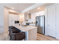 Modern kitchen with white cabinets, stainless steel appliances, and a large island with seating at 3131 N Central Ave # 3013, Phoenix, AZ 85012