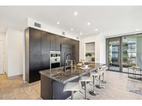 Modern kitchen with dark cabinetry, granite island, and stainless steel appliances at 7180 E Kierland Blvd # 1007, Scottsdale, AZ 85254