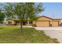 Single story house with three car garage and landscaped lawn at 25843 W Northern Lights Way, Buckeye, AZ 85326