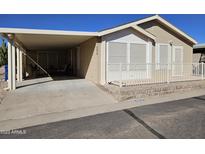 Tan mobile home with covered carport and white railing at 650 N Hawes Rd # 4956, Mesa, AZ 85207