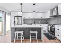 Modern kitchen with white cabinets, gray herringbone backsplash, and stainless steel appliances at 8055 E Thomas Rd # E117, Scottsdale, AZ 85251